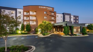 Un hotel Courtyard by Marriott con diseño moderno, estacionamiento y zonas ajardinadas.