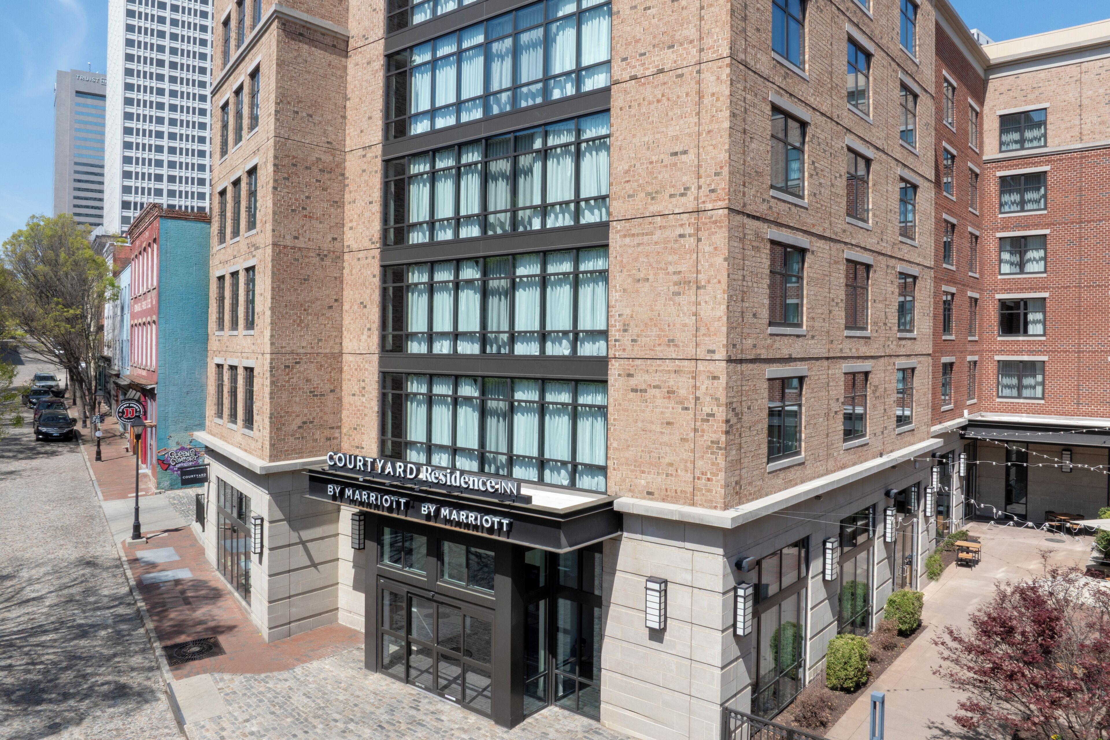 A multi-story brick building with large windows and a sign for 'Courtyard Residence Inn by Marriott.'