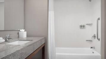 Un baño moderno con encimera de granito, dos lavamanos, ducha con puerta de vidrio y un inodoro.
