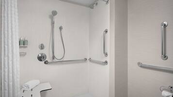 A modern bathroom with a shower, grab bars, a towel rack, and a toilet paper holder.