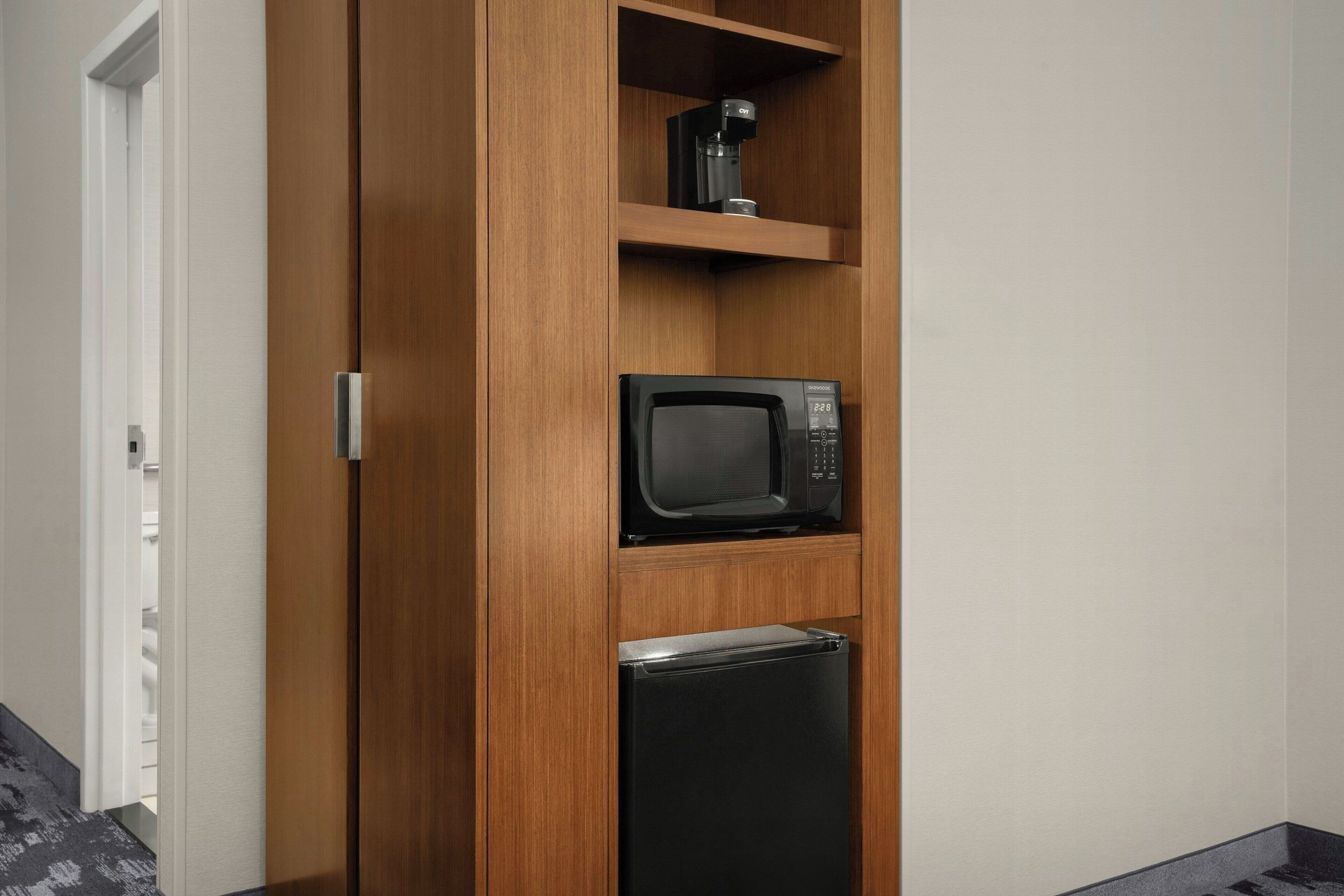 A wooden cabinet with a microwave and a coffee maker on top.