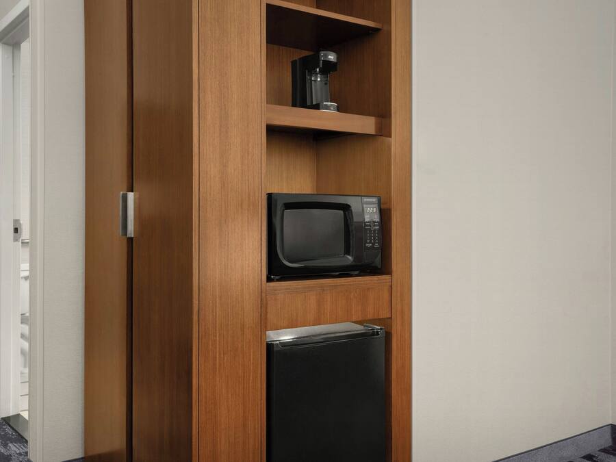 A wooden cabinet with a microwave and a coffee maker on top.