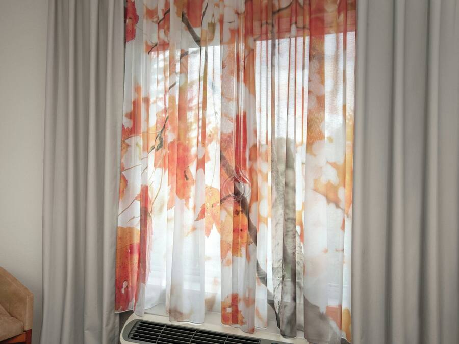 A window with sheer curtains featuring a leaf pattern.