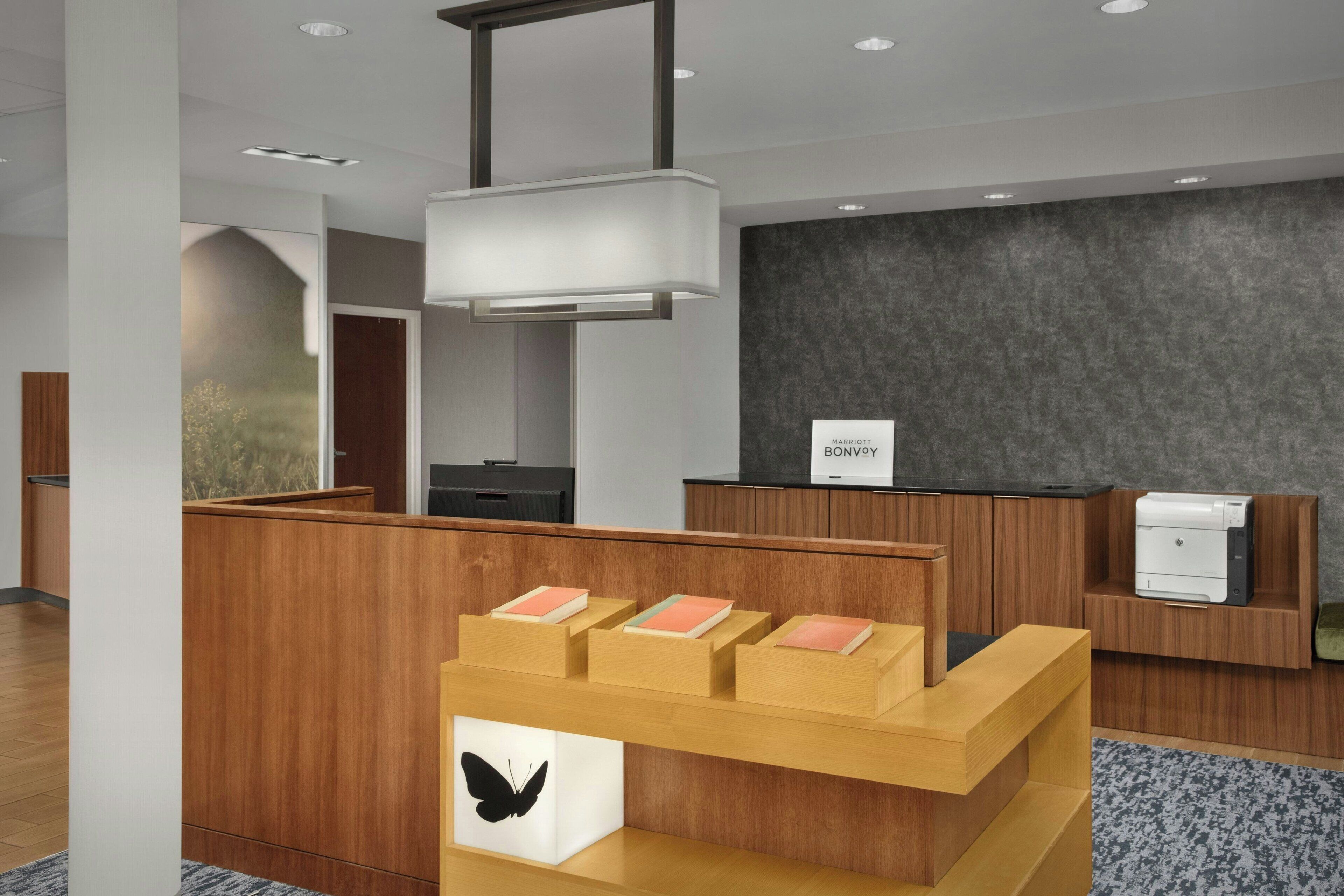 A modern reception desk with a wooden finish, a black butterfly decoration, and a sign for 'MARRIOTT BONVOY'.
