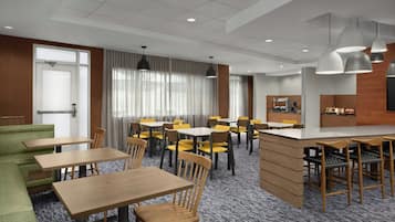 Een restaurantgedeelte in een hotel met meerdere tafels en stoelen, een bar en uitzicht op de stad.