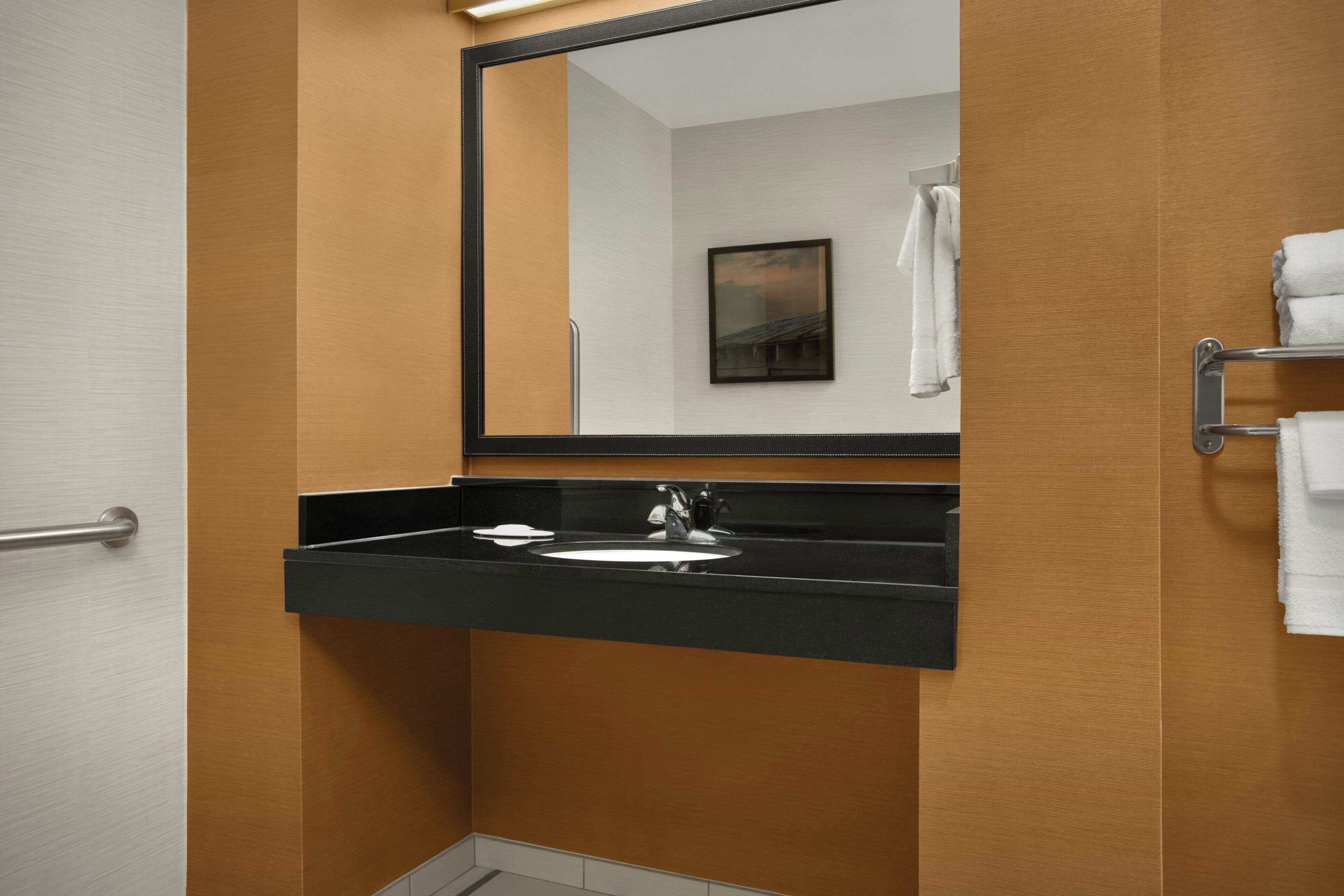 Une salle de bain avec un lavabo à vasque noire, un miroir et un porte-serviettes.