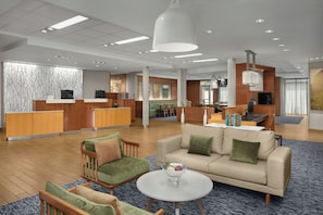 Un hall d’hôtel moderne comprenant un comptoir d’accueil, un espace salon et un espace repas.