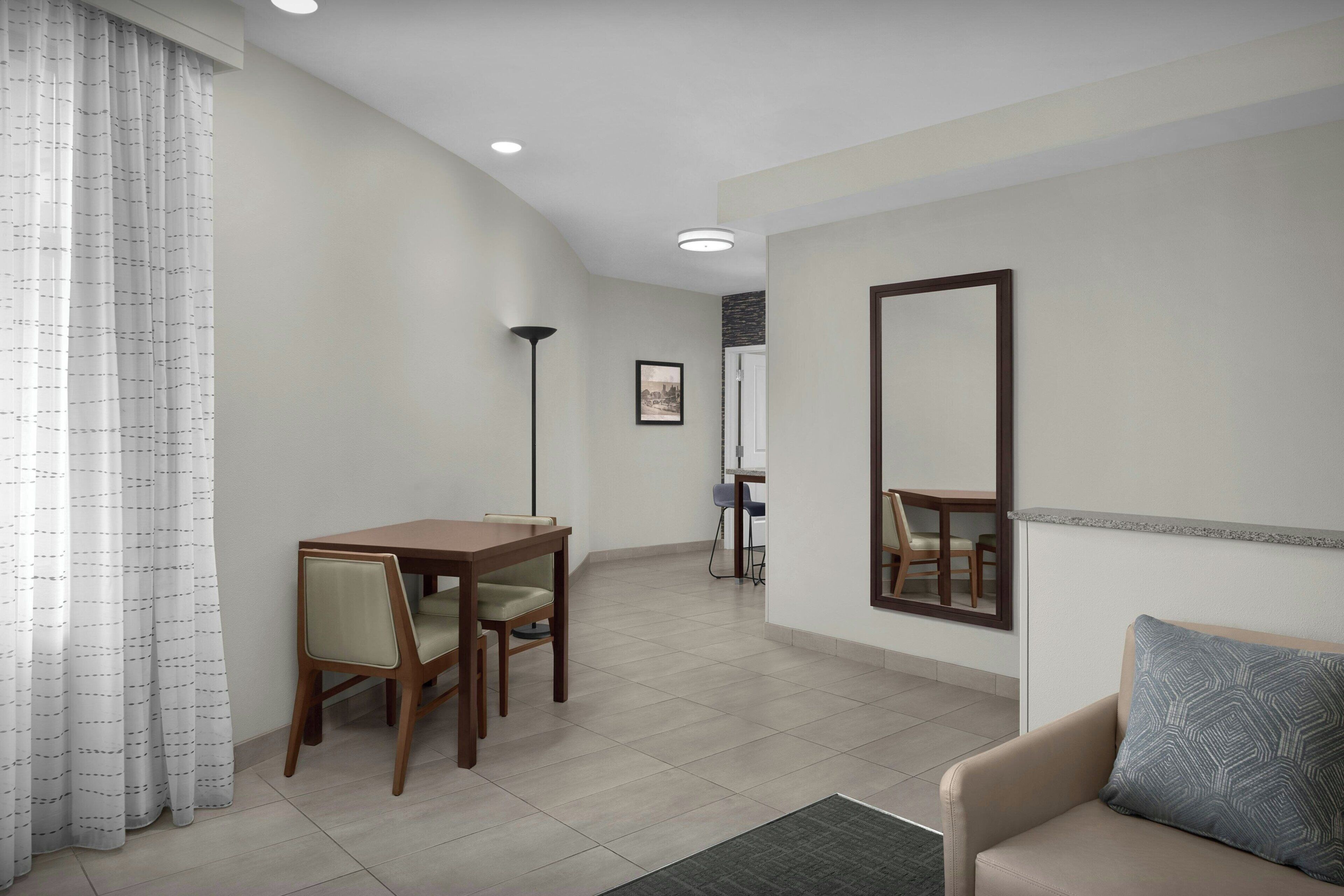 Una sala de estar moderna con comedor, un sofá, una mesa de centro y un espejo grande.