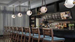 A bar area with wooden bar stools, hanging pendant lights, and a menu board. - Residence Inn by Marriott Richmond Downtown (Richmond)