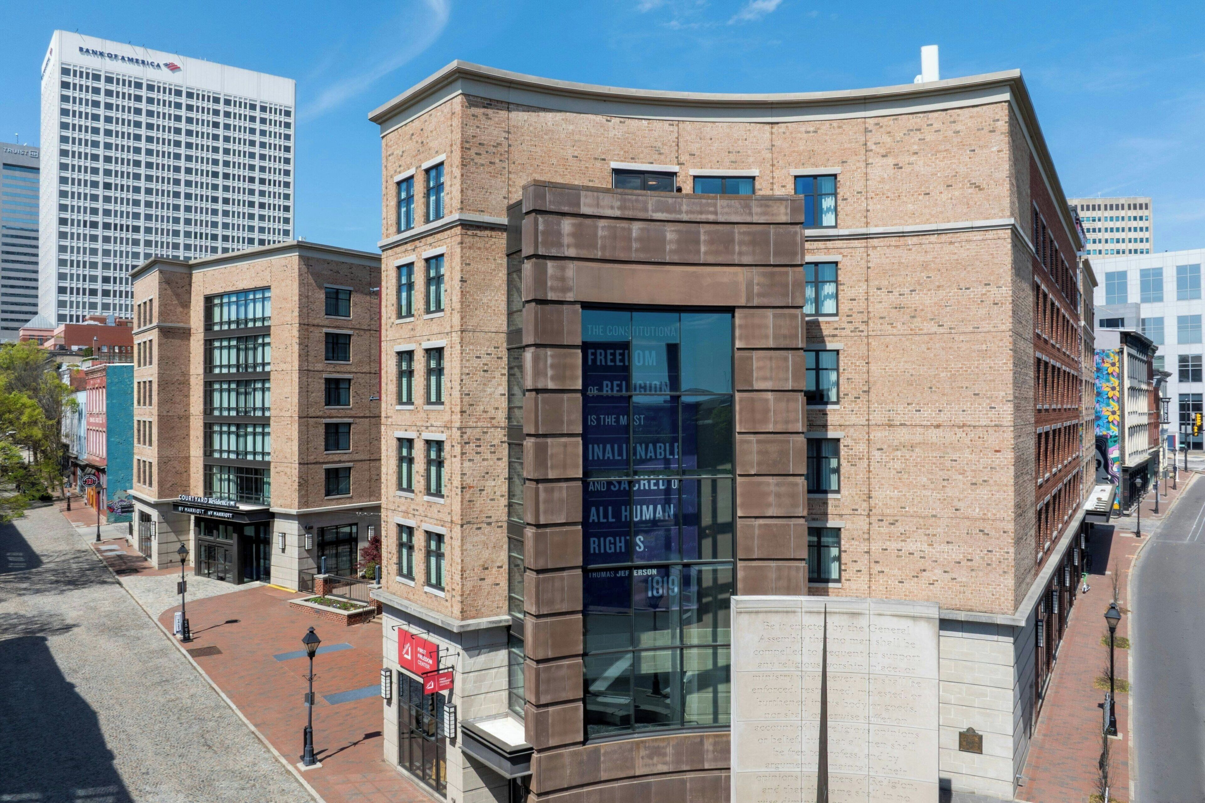 A multi-story building with a brick facade, large windows, and a clear sky.