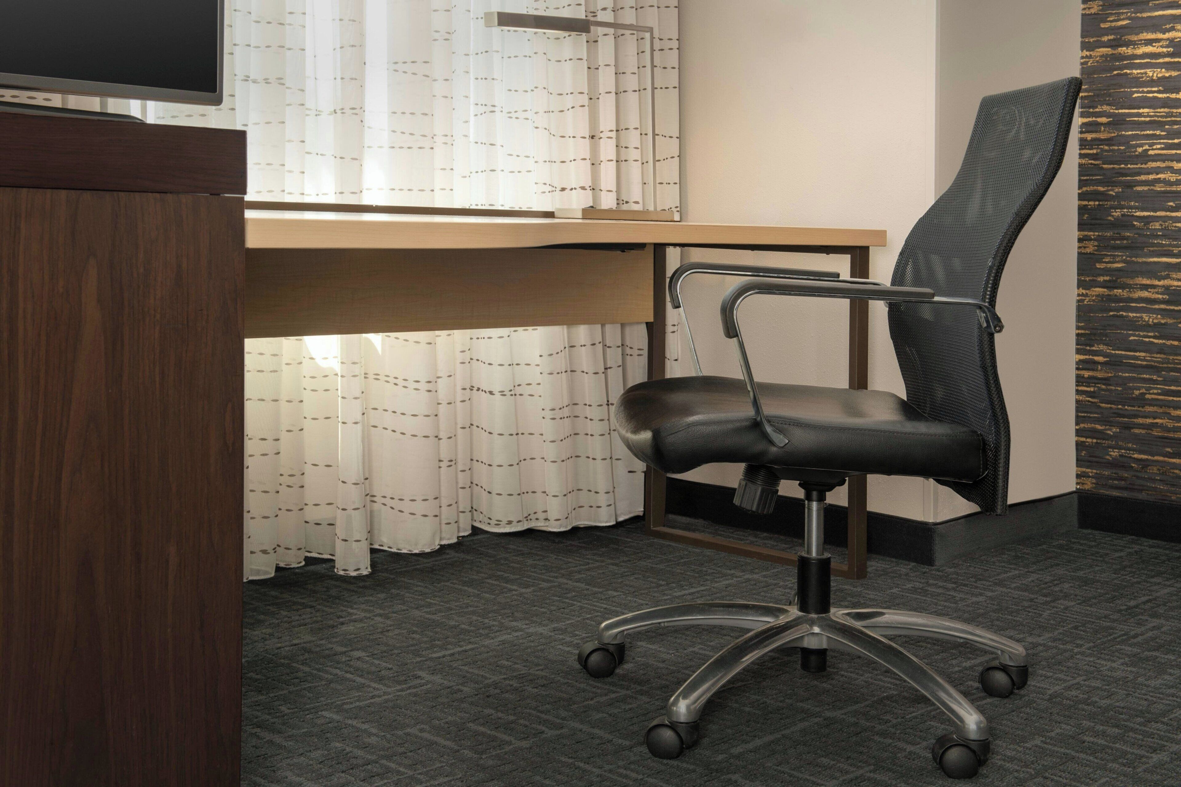 A modern office space with a desk, chair, and a television.