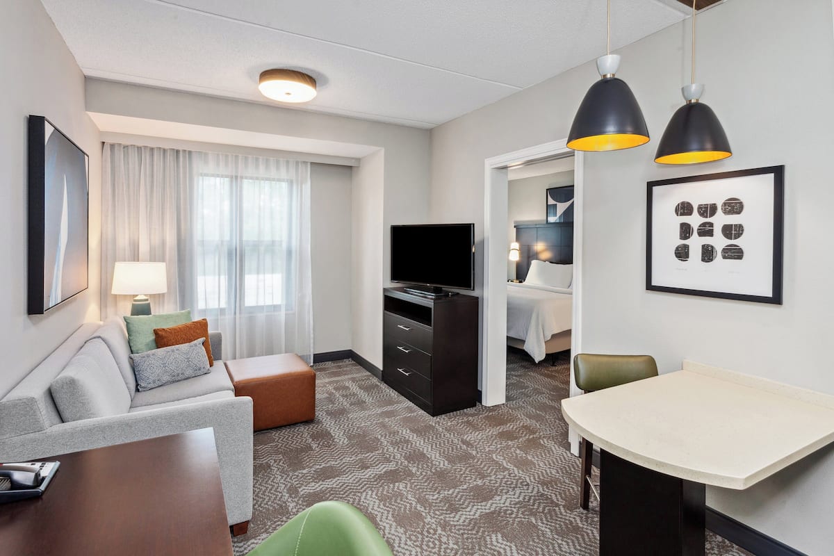 Une chambre d’hôtel avec un canapé, une télévision, une table à manger et un lit.