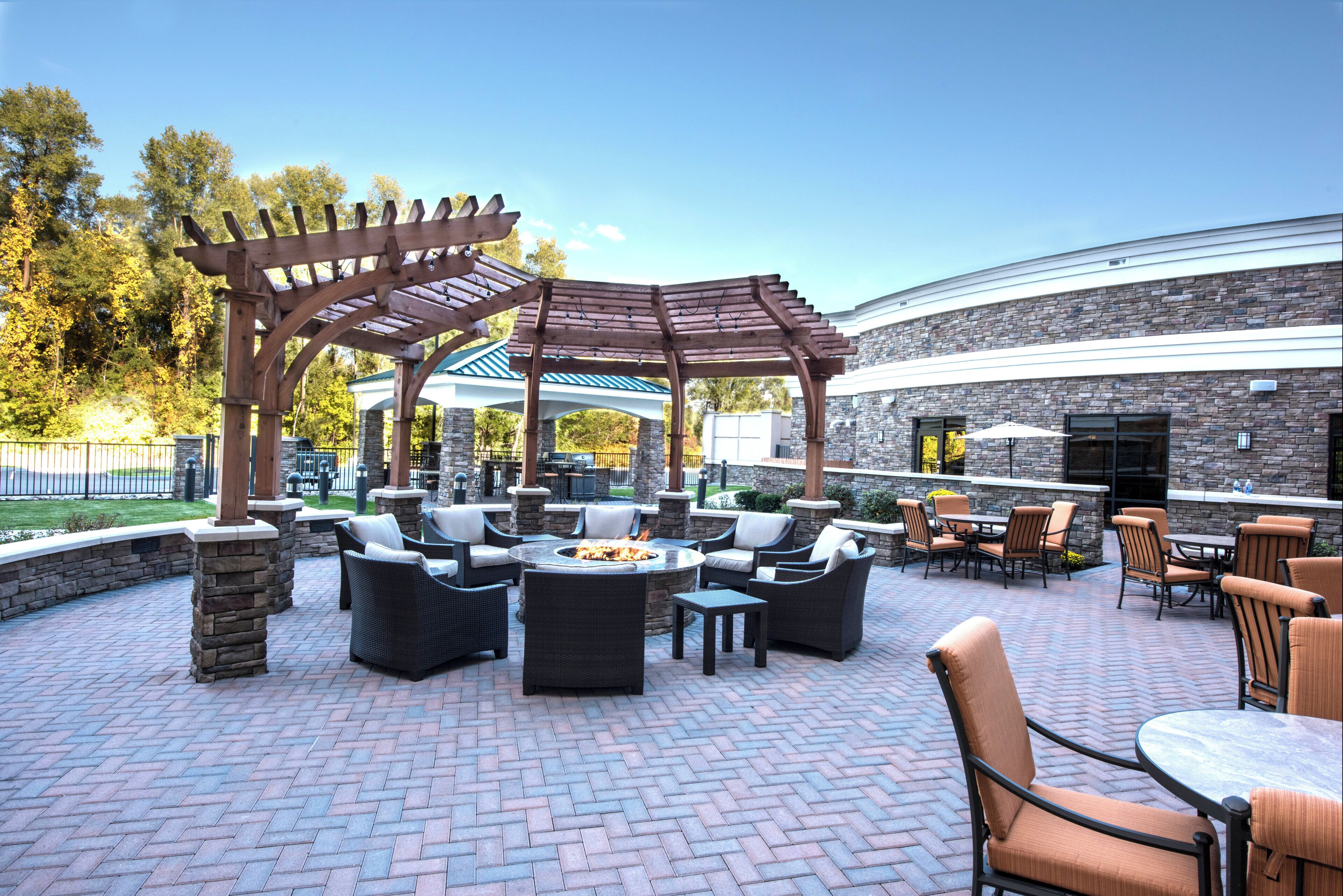 Eine Terrasse im Freien mit einer Pergola, einer Sitzgruppe und einem Feuerkorb.
