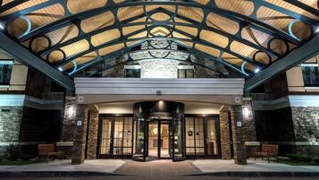 L’entrée d’un hôtel au design moderne, caractérisée par une porte d’entrée en verre, une façade en pierre et une structure de toit en métal.
