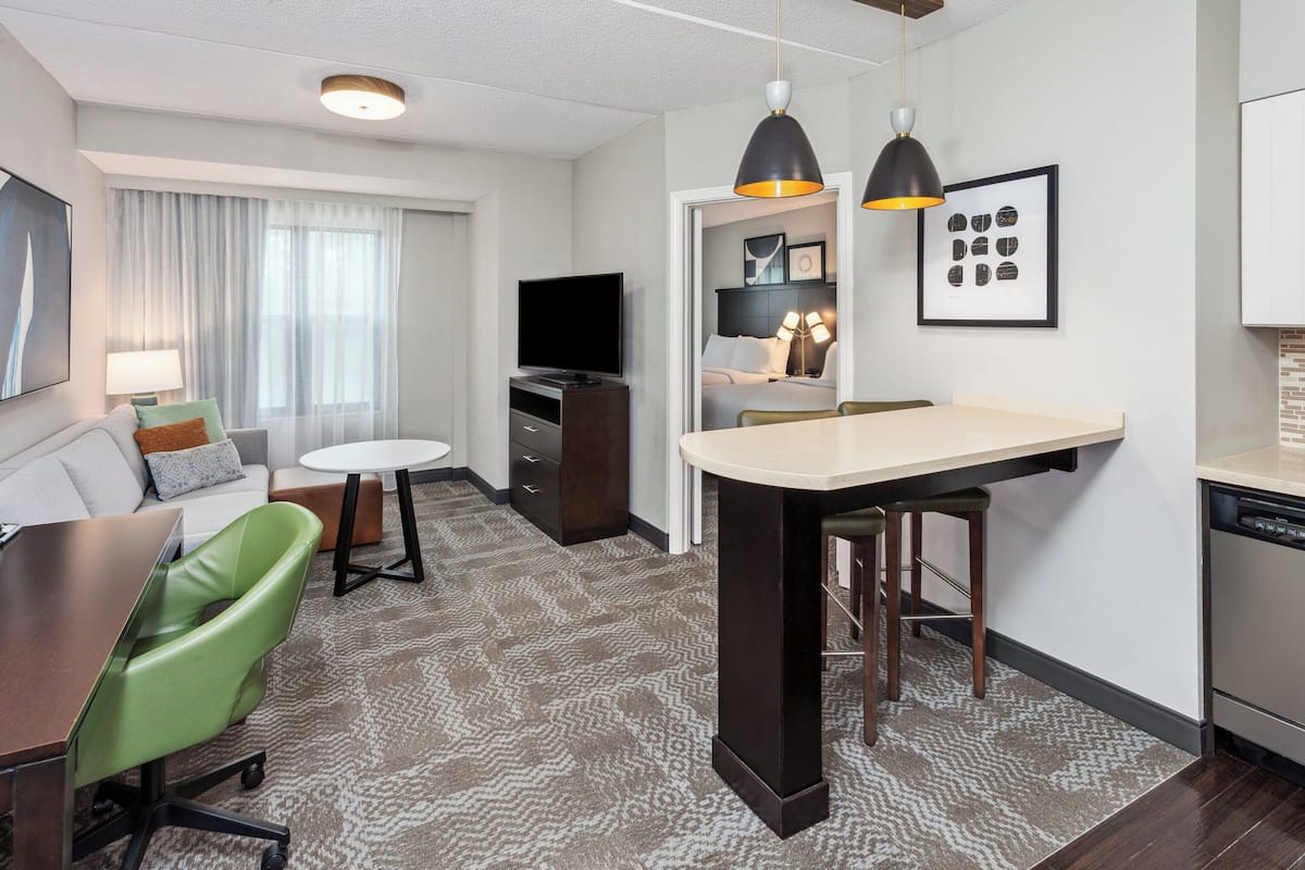 Une chambre d’hôtel moderne équipée d’un canapé, d’une table à manger, d’un coin cuisine et d’un téléviseur.