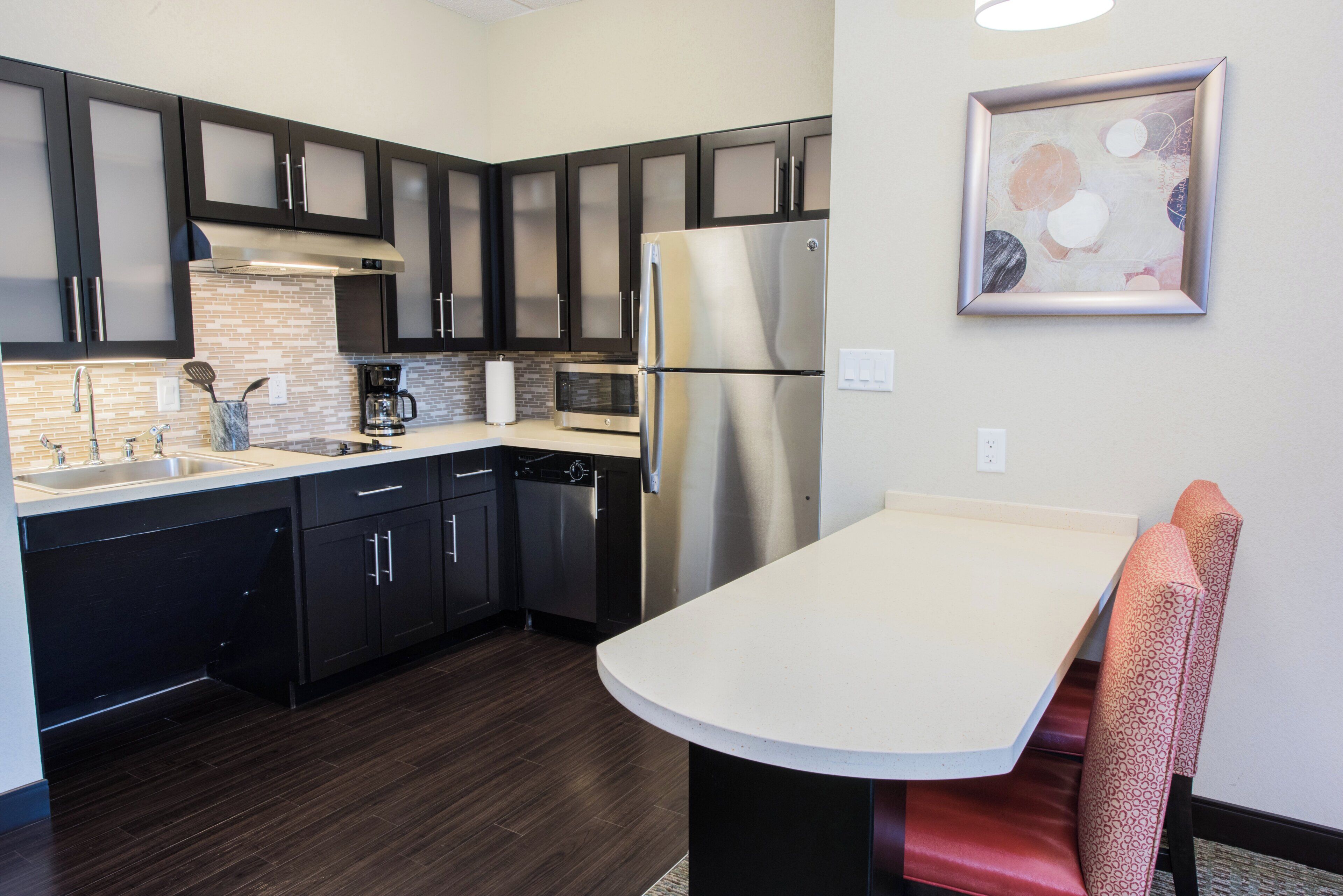 A modern kitchen with dark cabinets, stainless appliances, and a round dining table.