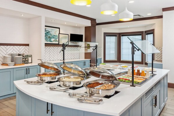 Un buffet proposant une variété de plats et d’ustensiles de service.