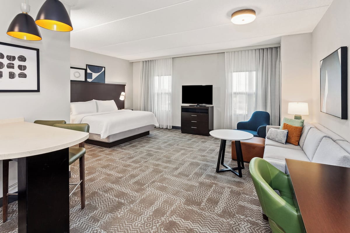 Une chambre d’hôtel comprenant un lit, un bureau, un canapé, une télévision et un coin repas.
