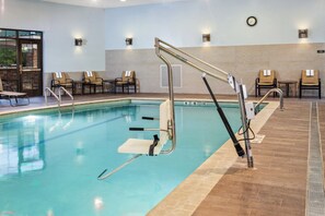 An indoor swimming pool with a diving board, lounge chairs, and a clock on the wall. - Staybridge Suites Albany Wolf Rd-Colonie Center by IHG (Albany)