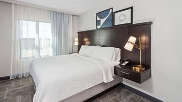 Hotelkamer met een groot bed, nachtkastje met een lamp en uitzicht op de stad.