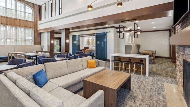 Een ruime lobby met een modulaire bank, een houten salontafel en een bar met krukken.