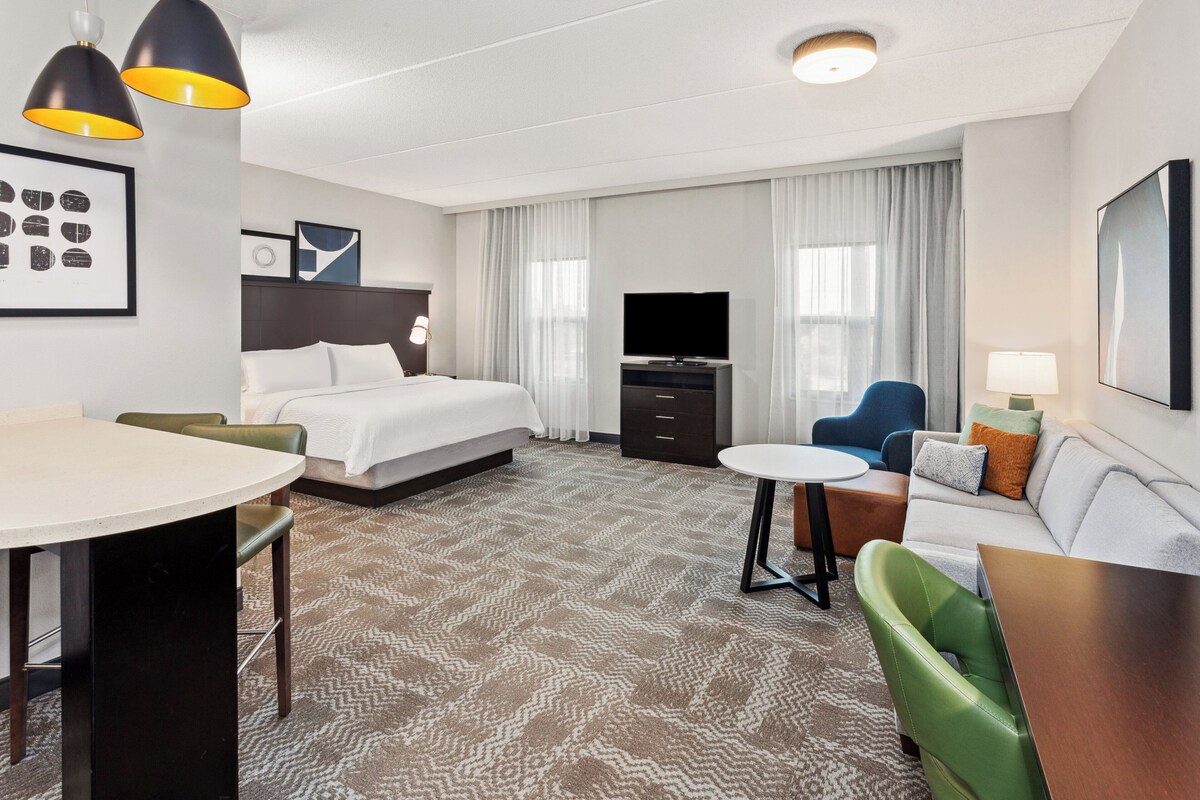 Une chambre d’hôtel comprenant un lit, un bureau, un canapé, une télévision et un coin repas.
