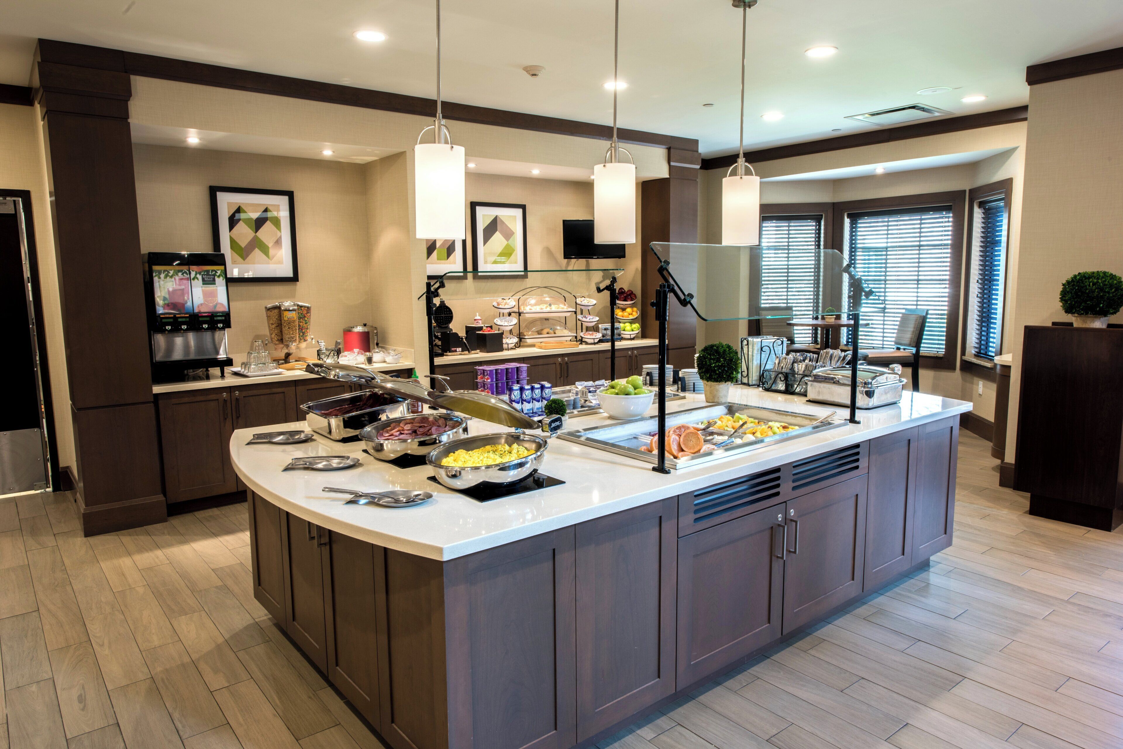 A breakfast buffet with various food options, a coffee machine, and a television screen.