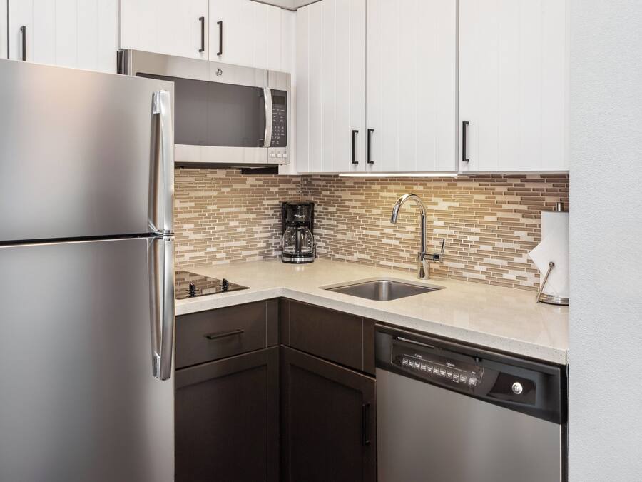 Una cocina moderna con electrodomésticos de acero inoxidable, cafetera y lavavajillas.