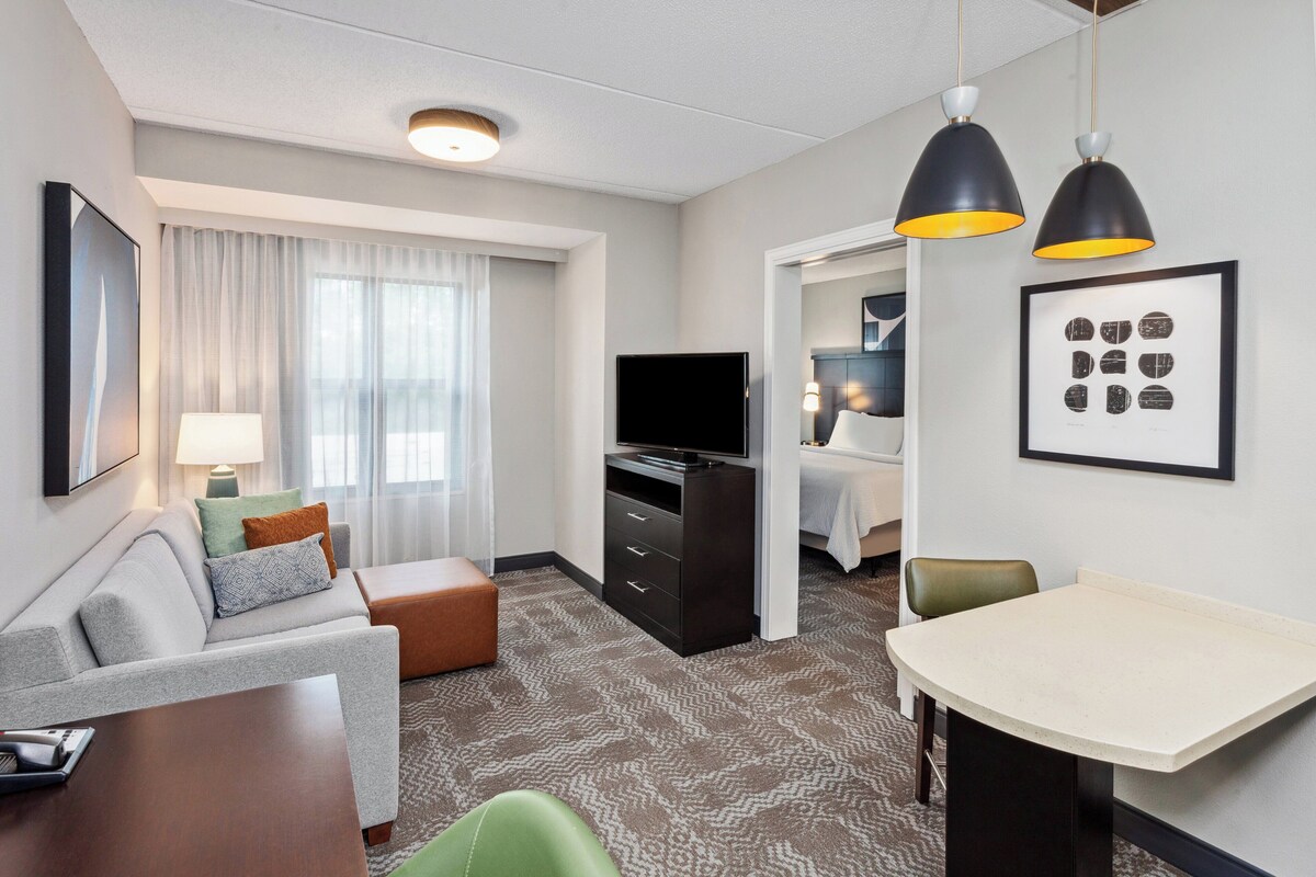 Une chambre d’hôtel avec un canapé, une télévision, une table à manger et un lit.