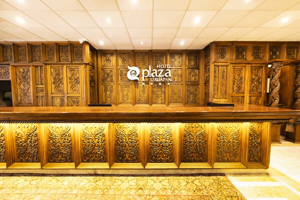Una recepción con intrincados grabados de madera y un letrero que indica Hotel Plaza Uruapan.