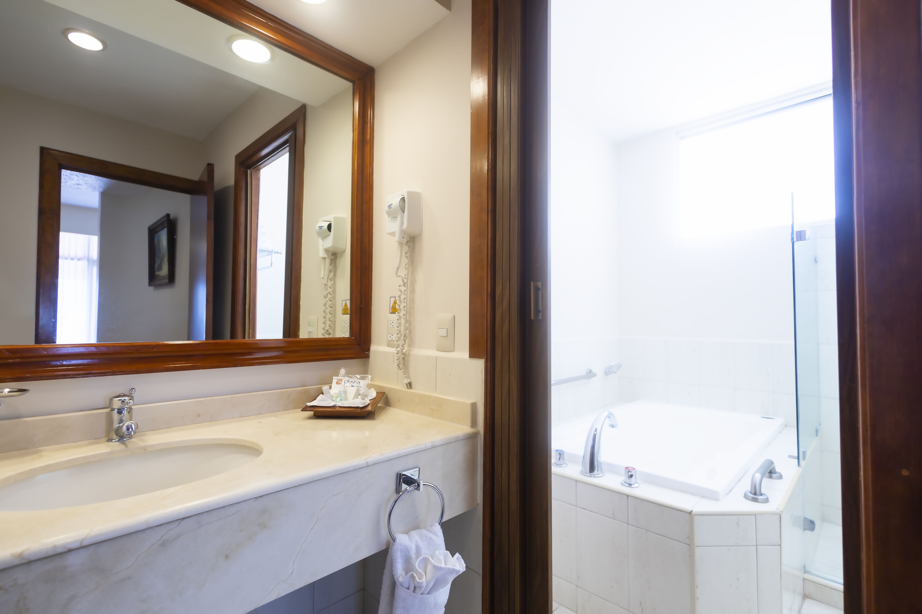 A bathroom with a large mirror, a sink, a towel rack, and a shower area.