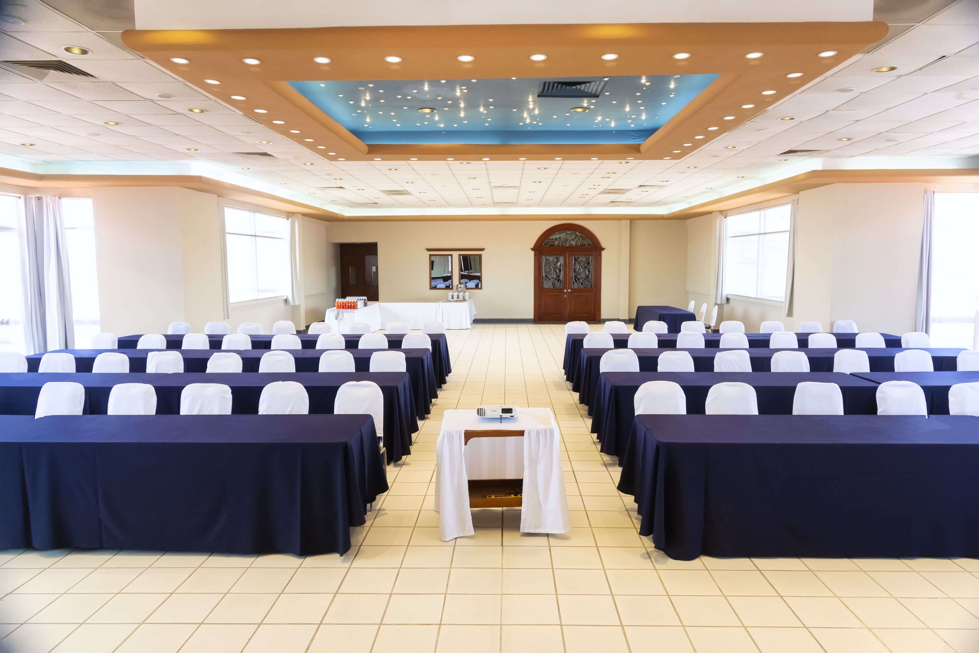 Un salón de conferencias con filas de sillas, un atril y un amplio arco de entrada.