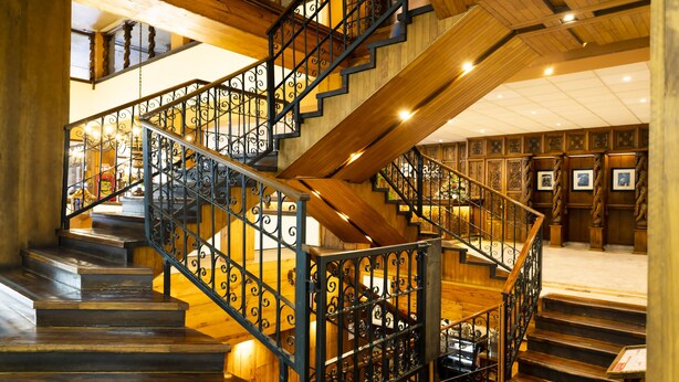 Una escalera de madera con barandillas de metal negro y piso de madera.