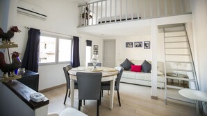 A spacious living area with a dining table, chairs, a sofa, and a balcony. - Residence Bouttau (Cannes)