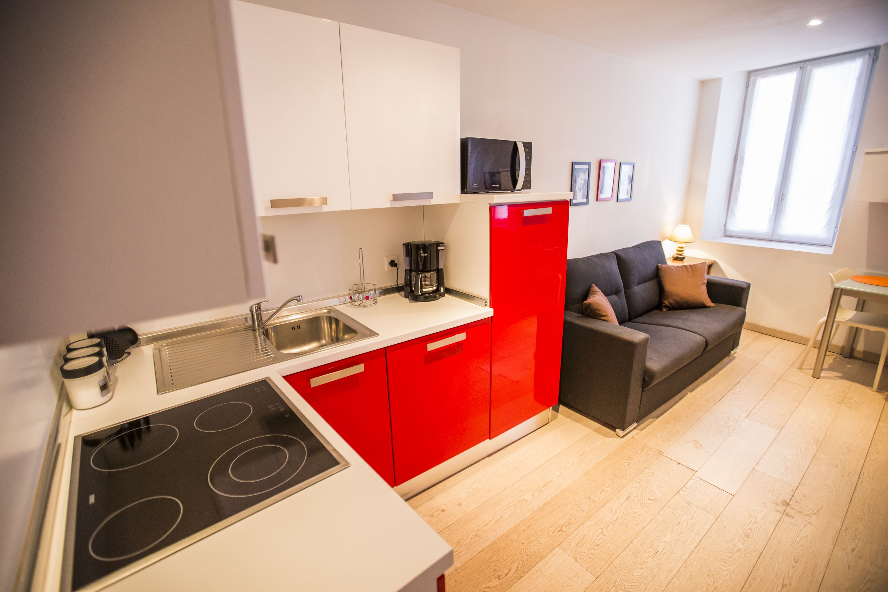 Una cocina compacta con un gabinete rojo, un microondas negro y una cafetera.