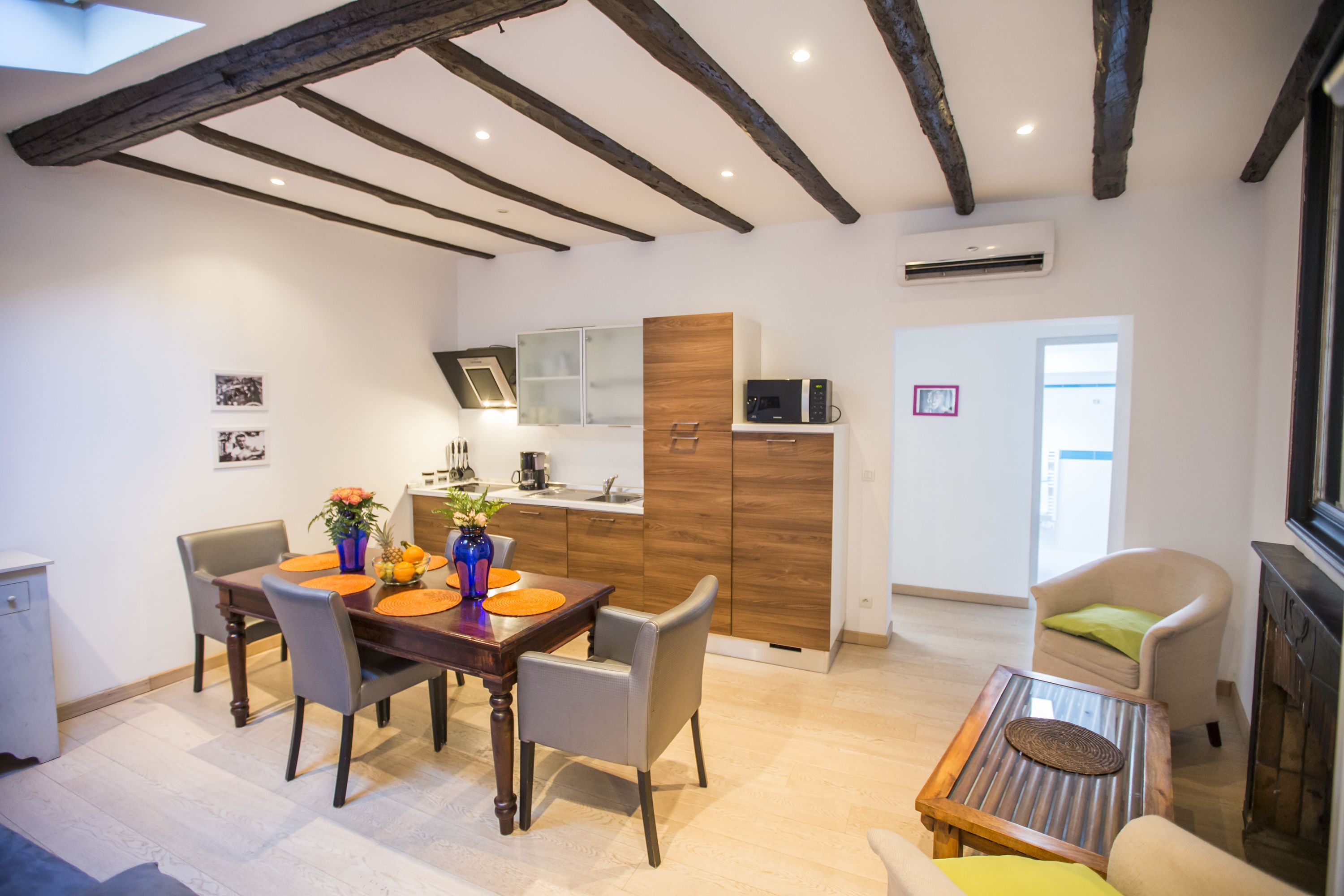 Un comedor moderno con una mesa y sillas de madera, una cocina con armarios de madera y un rincón de descanso acogedor con sofá y sillón.