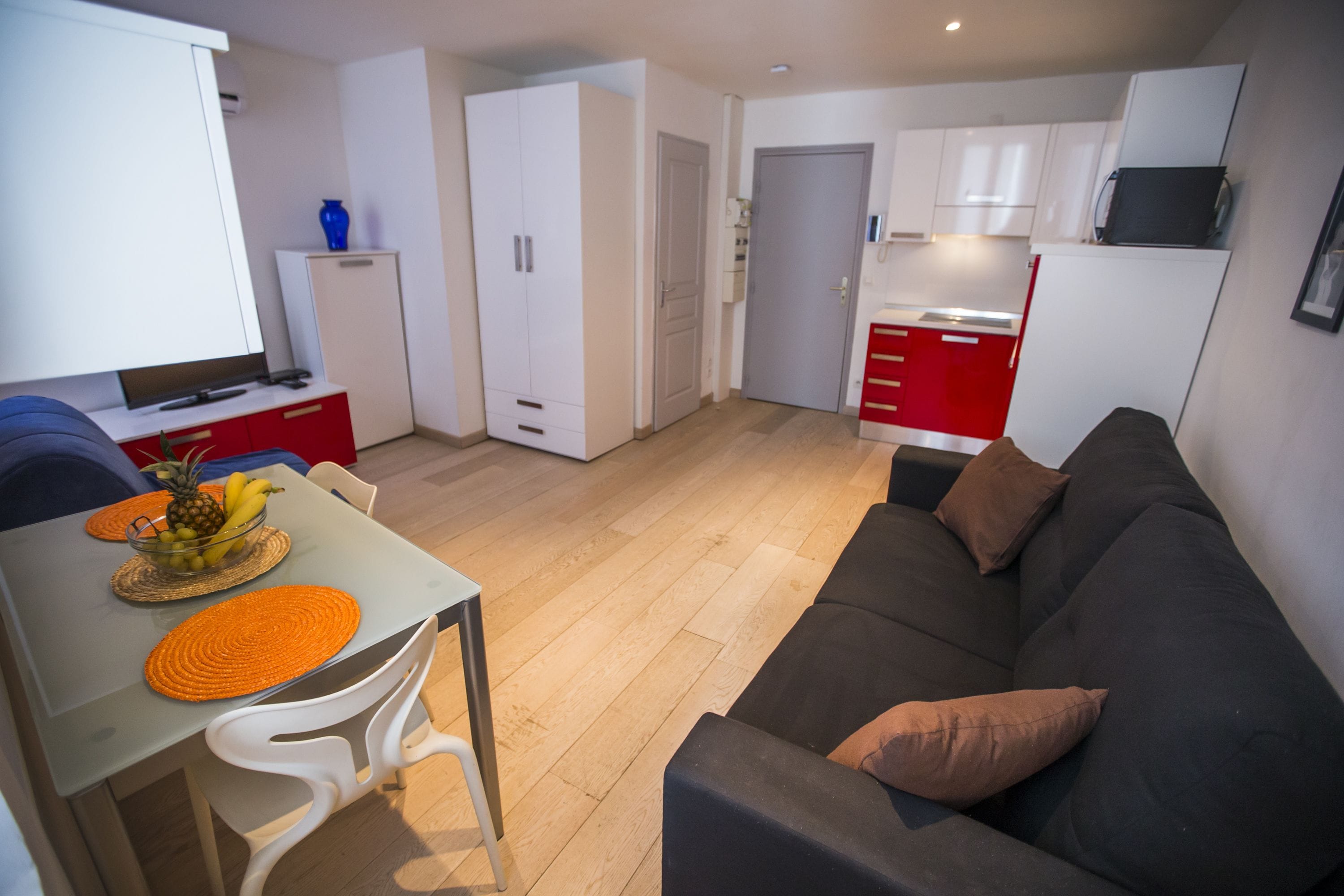 A compact living space with a dining area, kitchenette, and a sofa.