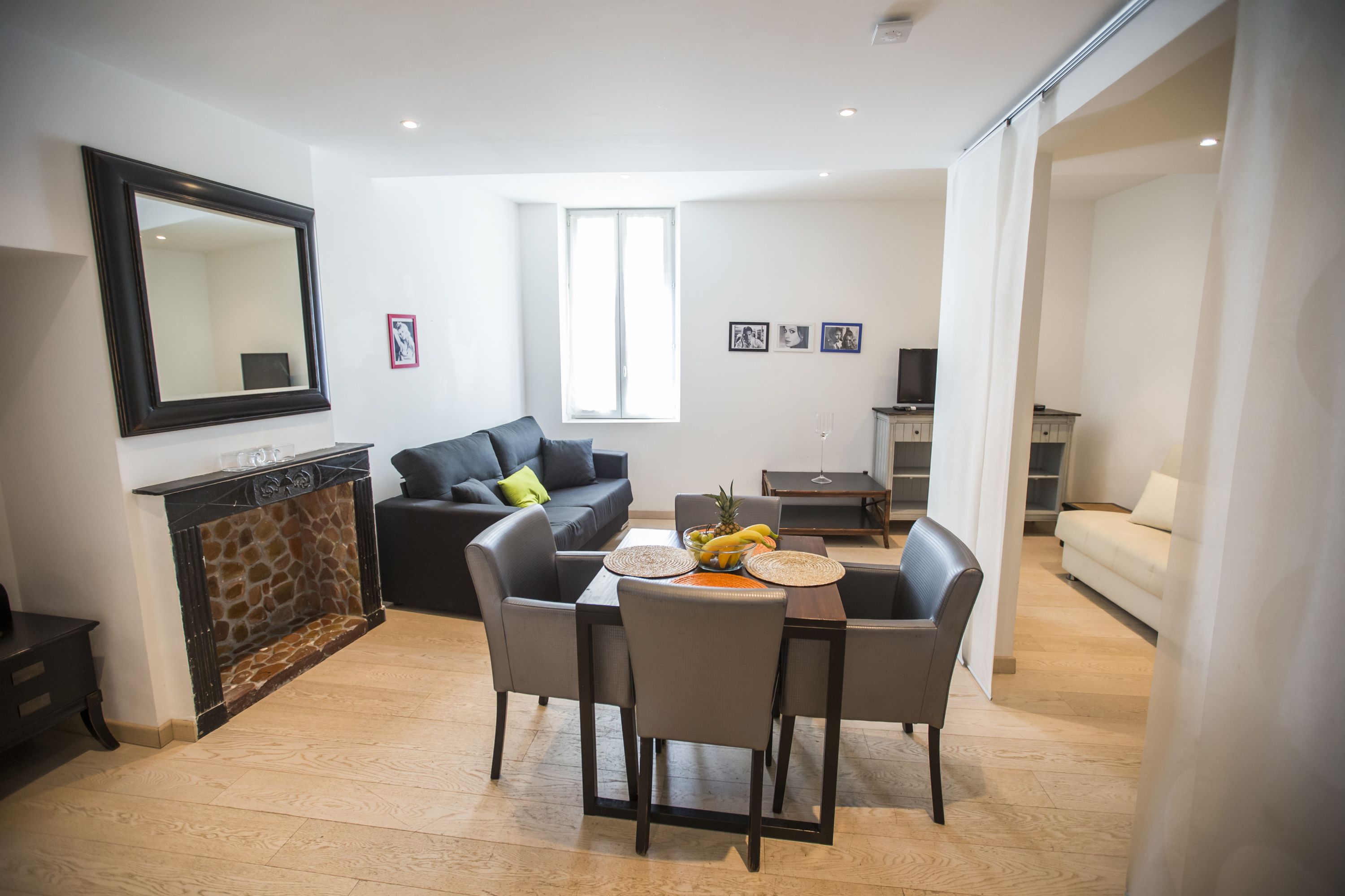Una sala moderna con chimenea, un comedor con mesa y sillas, un sofá y un espejo grande en la pared.