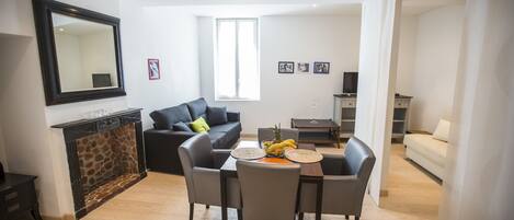 Una sala moderna con chimenea, un comedor con mesa y sillas, un sofá y un espejo grande en la pared.