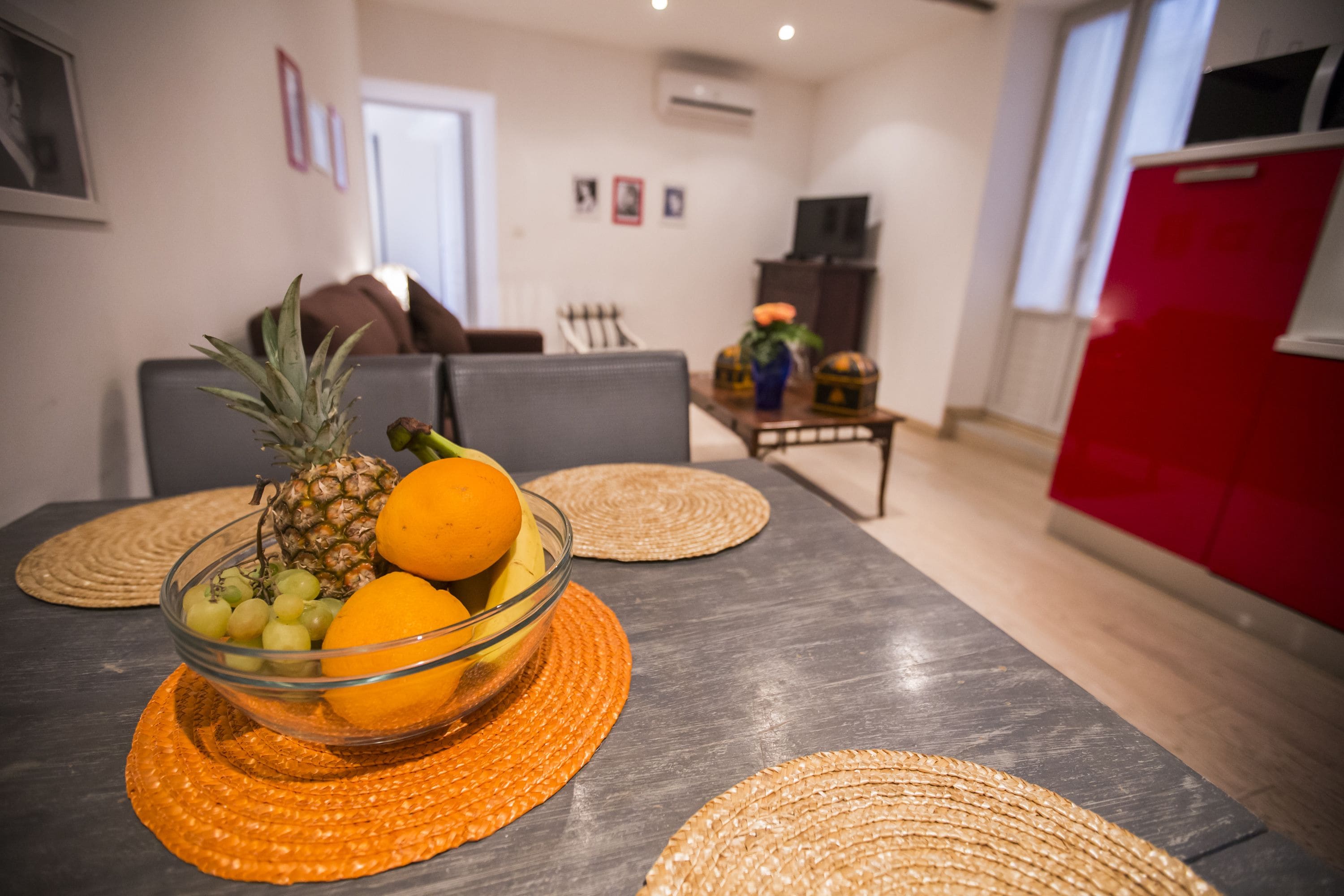 Una mesa de comedor con un frutero y posavasos.