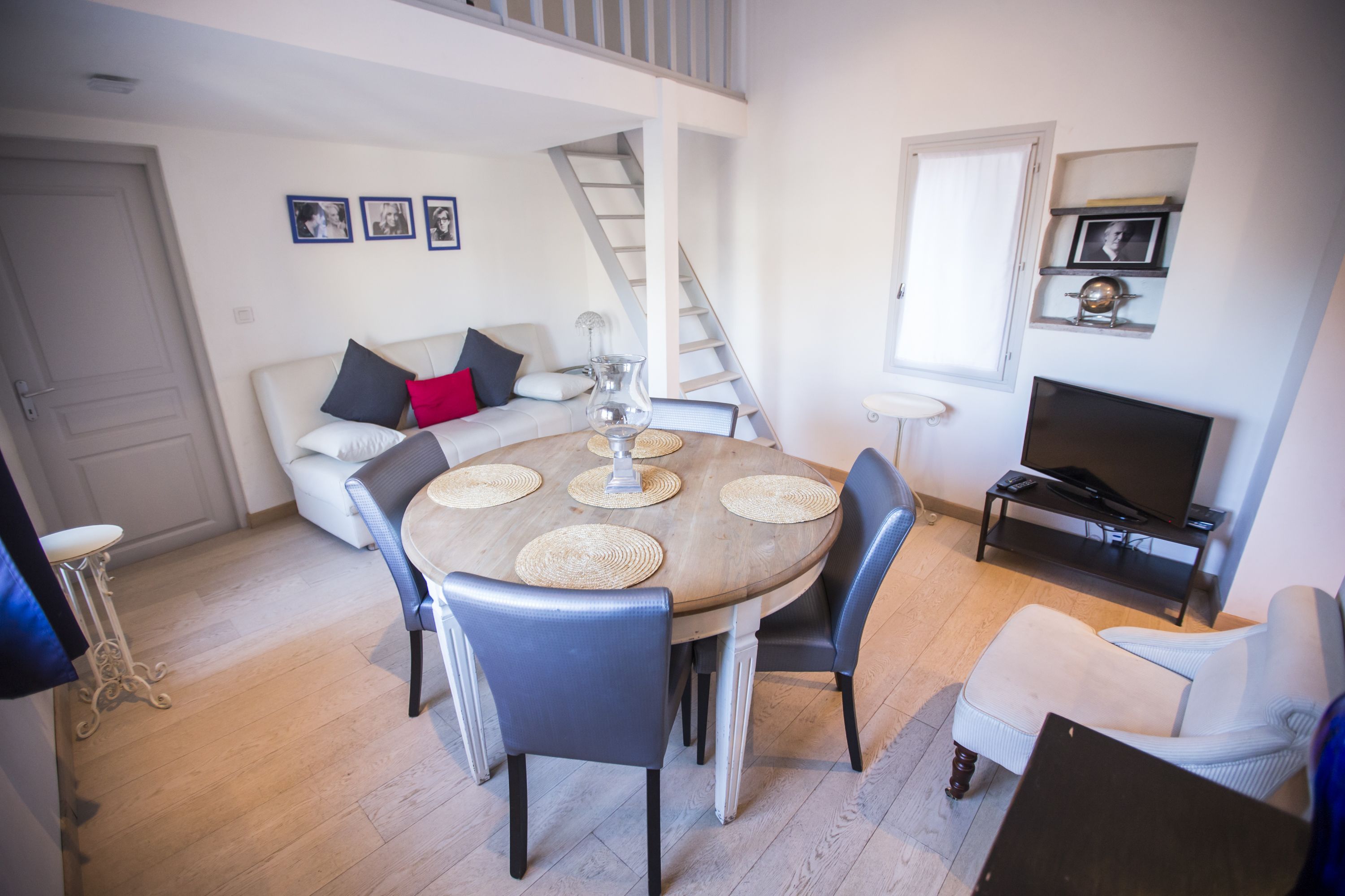 A dining area with a round table, chairs, and a television in the background.