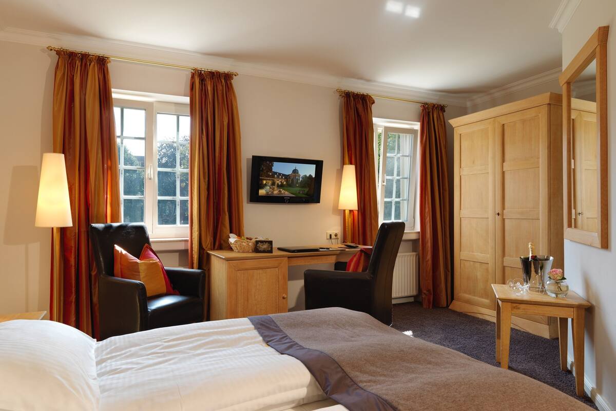 Une chambre d’hôtel comprenant un lit, un bureau, deux chaises, une télévision et une armoire.