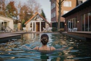 Una persona nadando en una piscina con edificios al fondo.