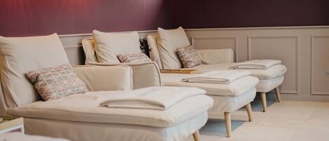 A spa room with multiple massage tables, a window with a view, and wall-mounted lighting.