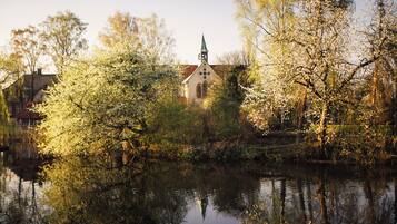 A church with a steeple and a reflection in the water.