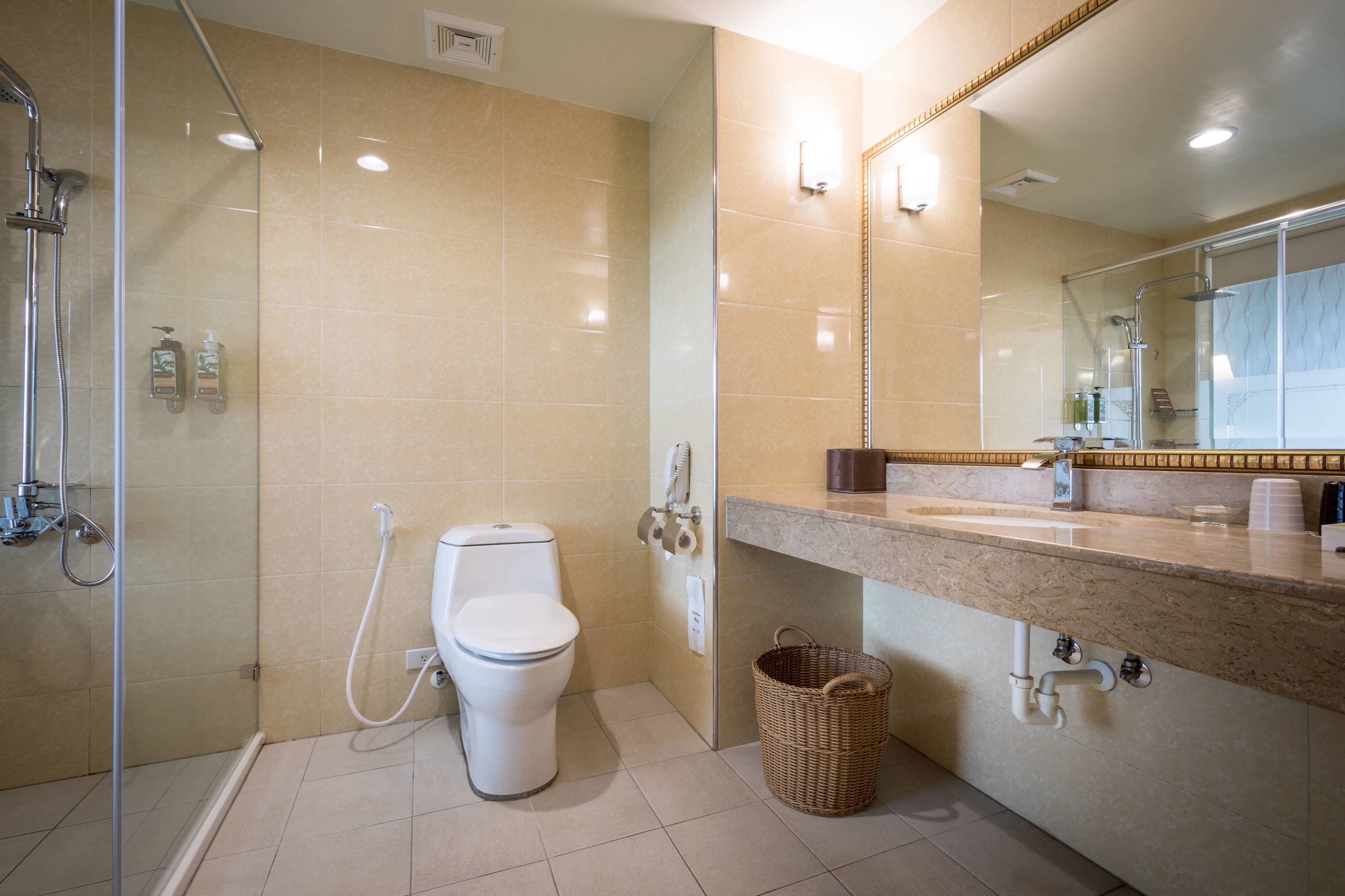A modern bathroom with a glass-enclosed shower, a toilet, a sink with a marble countertop, and a mirror above the sink.