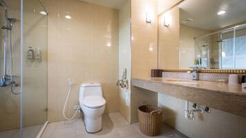 A modern bathroom with a glass-enclosed shower, a toilet, a sink with a marble countertop, and a mirror above the sink.