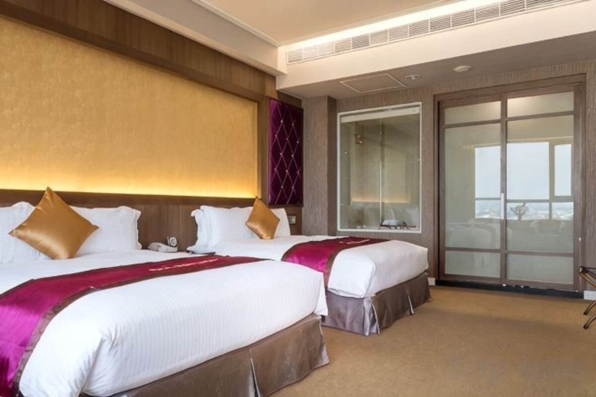 Habitación de hotel con dos camas, un espejo grande y una puerta corrediza de vidrio al exterior.