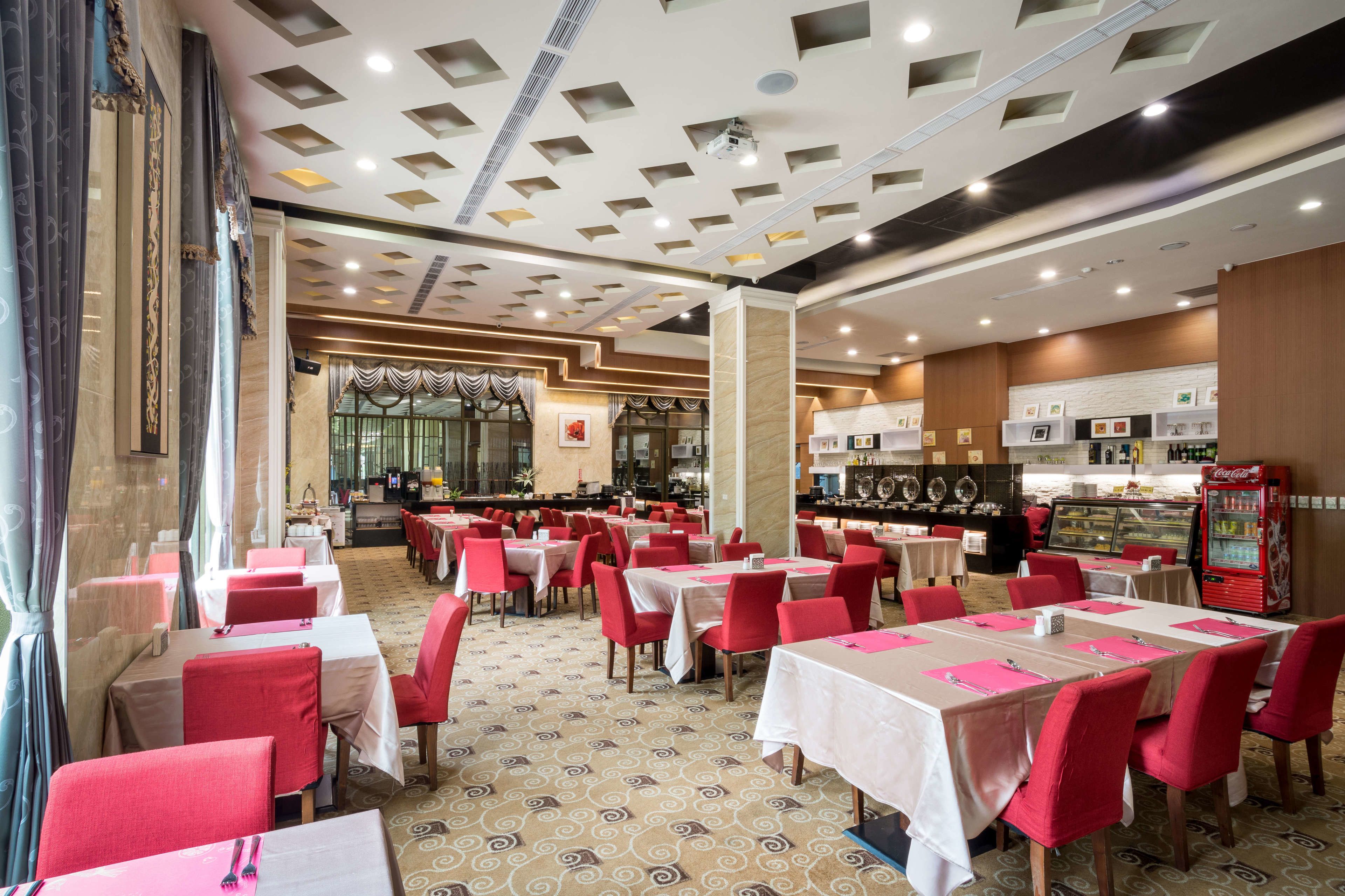 Un restaurant avec des tables rouges et blanches, un coin bar et un distributeur automatique de Coca-Cola.
