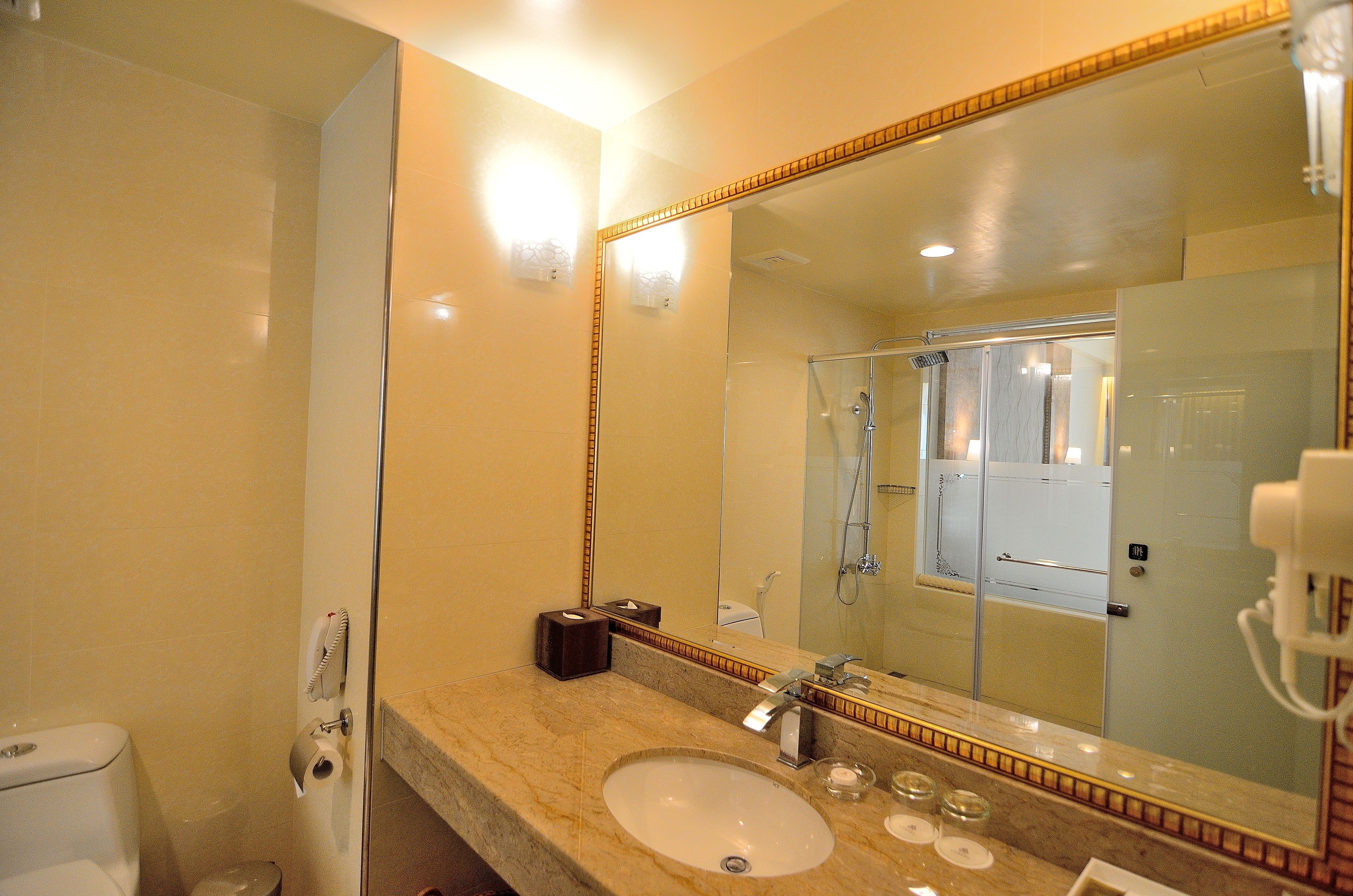 A bathroom with a marble sink, a large mirror, and a glass shower enclosure.